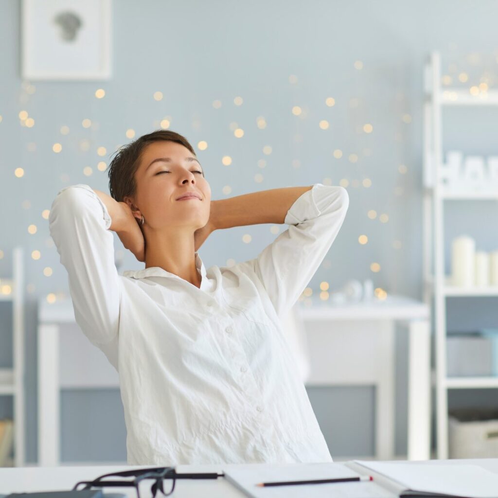 woman relaxed leaning in a chair with her head resting on her hands in back of her because she is living within her means